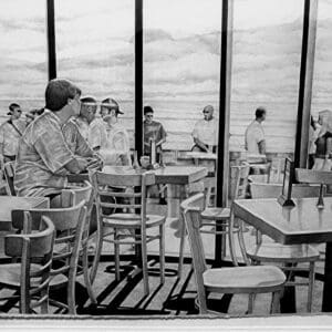 A group of people sitting at tables in front of windows.